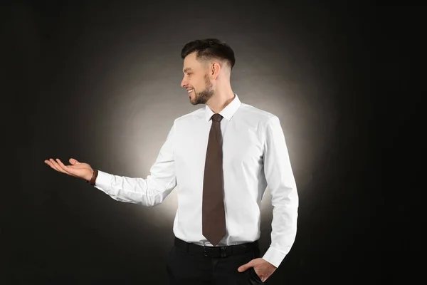 Ung affärsman höll något på färgbakgrund — Stockfoto