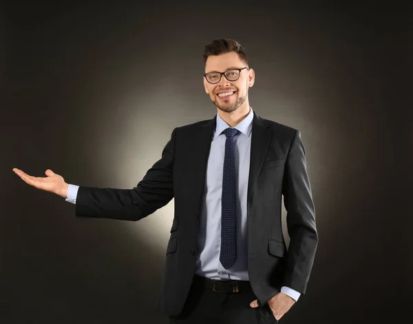 Young businessman holding something on color background — Stock Photo, Image