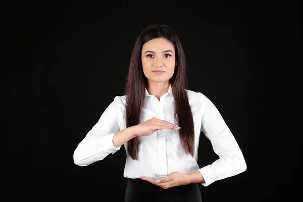 Junge Geschäftsfrau hält etwas auf schwarzem Hintergrund — Stockfoto