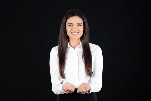 Young businesswoman holding something on black background — Stock Photo, Image