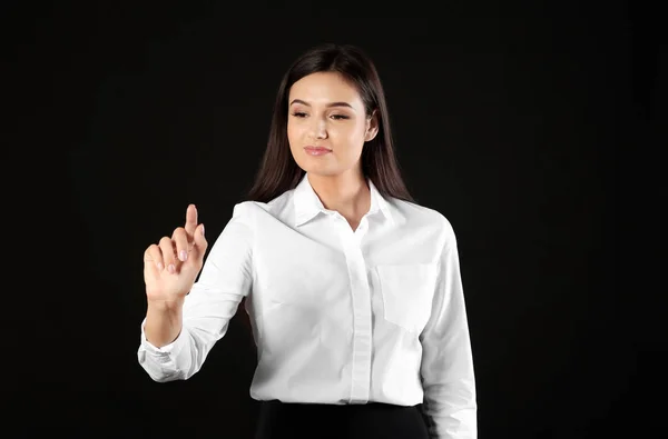 Junge Geschäftsfrau mit virtuellem Bildschirm auf schwarzem Hintergrund — Stockfoto