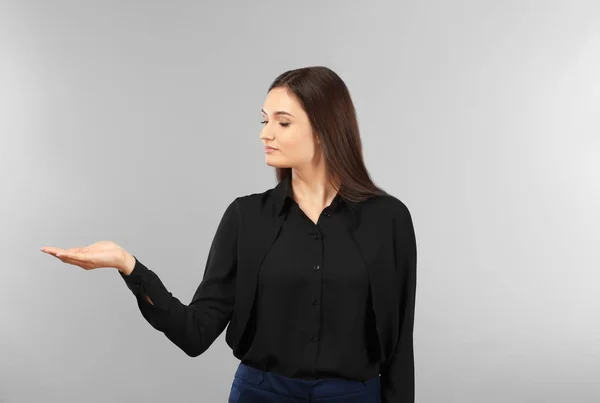 Молода бізнес-леді тримає щось на сірому фоні — стокове фото