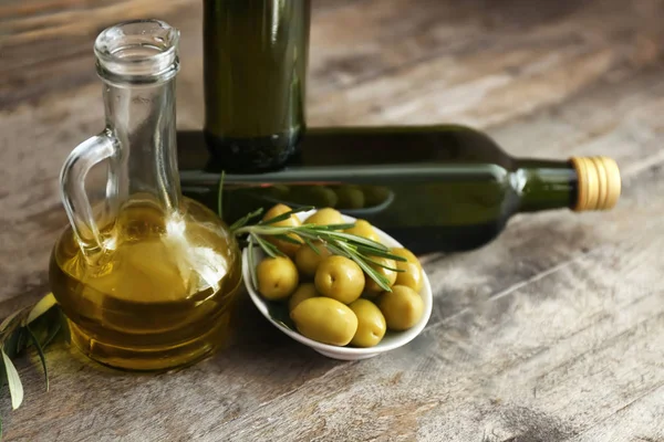 Olives and oil on wooden background — Stock Photo, Image