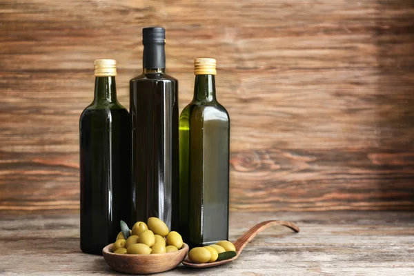 Composition with olives and oil in bottles on wooden background — Stock Photo, Image