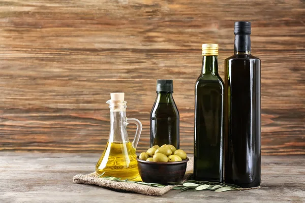 Composición con aceite de oliva en botellas y jarra sobre fondo de madera — Foto de Stock