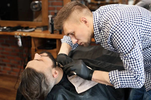 Barbier professionnel travaillant avec le client dans le salon de coiffure — Photo