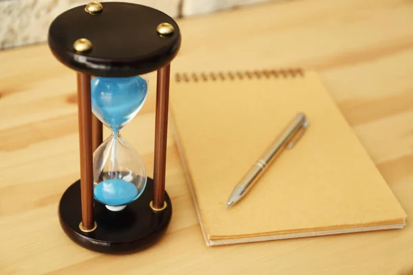 Timglas och anteckningsbok på träbord. Time management koncept — Stockfoto