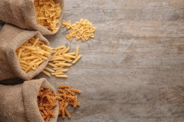 Ahşap arka plan üzerinde farklı pişmemiş makarna ile çanta
