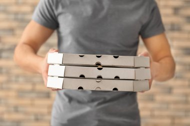 Teslimatçı tuğla duvar zemin üzerine karton pizza kutuları ile