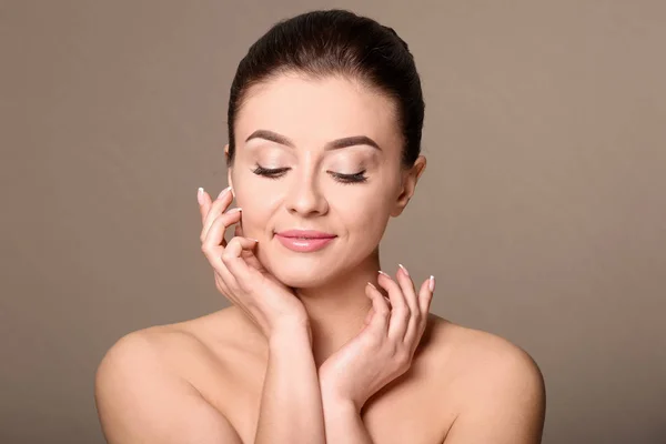 Mooie jonge vrouw met een zijdezachte huid na kuur op kleur achtergrond — Stockfoto