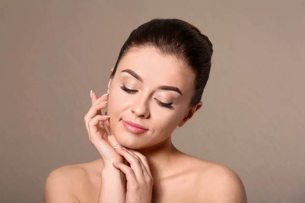 Mooie jonge vrouw met een zijdezachte huid na kuur op kleur achtergrond — Stockfoto