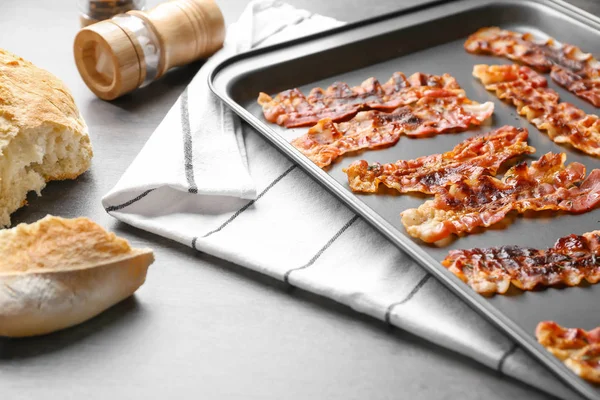 Baking sheet with bacon rashers on table — Stock Photo, Image