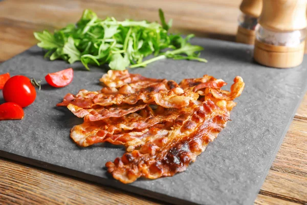 Fried bacon rashers on slate plate