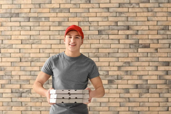 Entrega homem com caixas de pizza de papelão no fundo da parede de tijolo — Fotografia de Stock