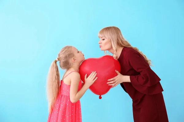 Ritratto di bambina carina e sua madre con palloncino su sfondo di colore — Foto Stock