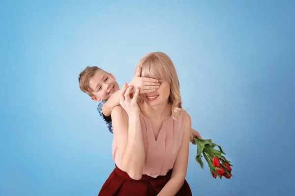 Mignon petit garçon surprenant sa mère avec bouquet de tulipes sur fond gris — Photo