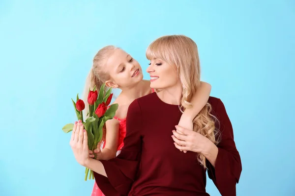 Retrato de linda niña y su madre con ramo de tulipanes en el fondo de color — Foto de Stock