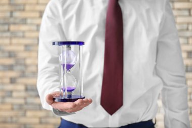 Bulanık arka planda, closeup kum saati tutan adam. Zaman yönetimi kavramı