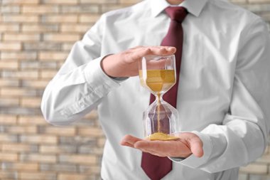 Bulanık arka planda, closeup kum saati tutan adam. Zaman yönetimi kavramı