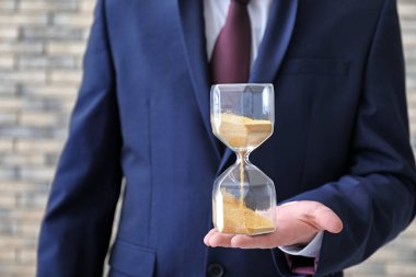 Bulanık arka planda, closeup kum saati tutan adam. Zaman yönetimi kavramı