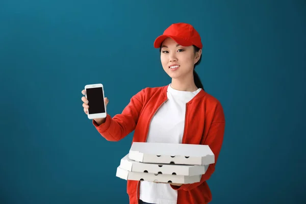 Asiatische Frau mit Pizzakartons und Handy auf farbigem Hintergrund. Essenslieferdienst — Stockfoto