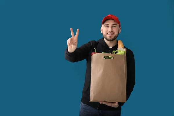年轻男子与产品在纸袋上的颜色背景。食品配送服务 — 图库照片