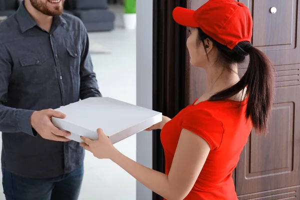 Mujer joven entregando comida al cliente en la puerta — Foto de Stock