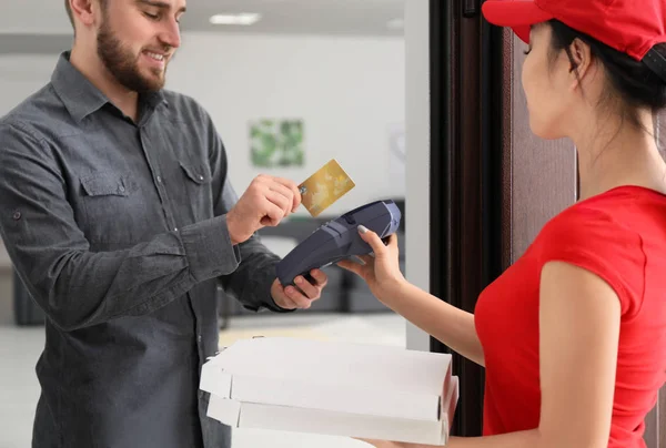 Young man using bank terminal for credit card payment at doorway. Food delivery service — Stock Photo, Image