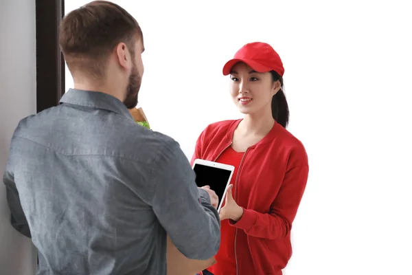 Young man signing on tablet for food delivery at doorway — Stock Photo, Image