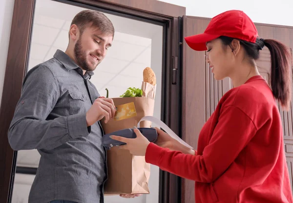 Young man using bank terminal for credit card payment at doorway. Food delivery service — Stock Photo, Image