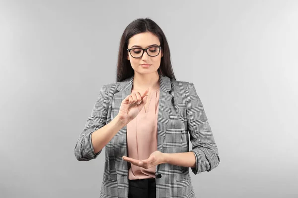 Young businesswoman using virtual screen on gray background — Stock Photo, Image