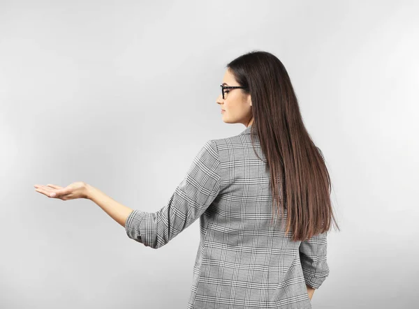 Young businesswoman holding something on gray background — Stock Photo, Image
