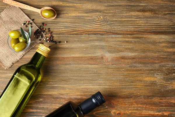 Плоская композиция с оливками и маслом на деревянном фоне — стоковое фото