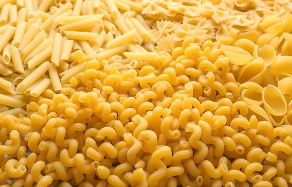 Different uncooked pasta as background, closeup — Stock Photo, Image