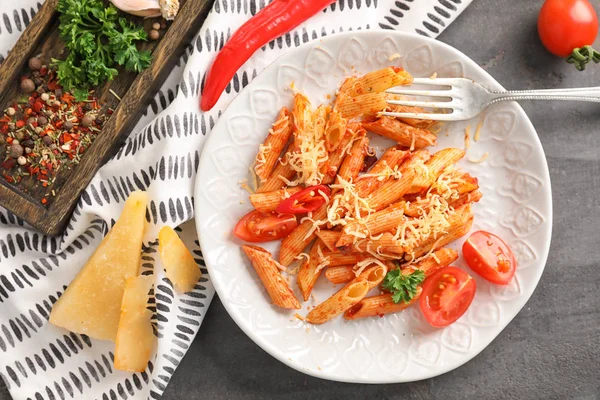 Plaat van smakelijke penne pasta met tomatensaus op grijze tafel — Stockfoto