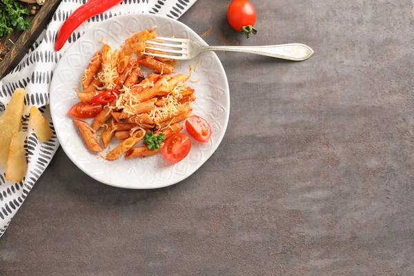 Plate of tasty penne pasta with tomato sauce on grey table — Stock Photo, Image