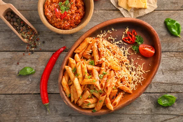 Plaat van smakelijke penne pasta met tomatensaus op houten tafel, bovenaanzicht — Stockfoto