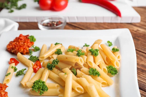 Plato con sabrosa pasta de penne y salsa boloñesa en la mesa de madera, primer plano — Foto de Stock