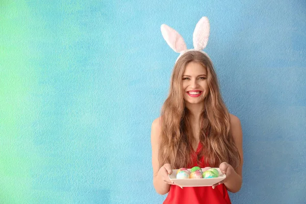 Paskalya yumurtaları ve tavşan kulakları renk arka plan üzerinde olan güzel kadın — Stok fotoğraf