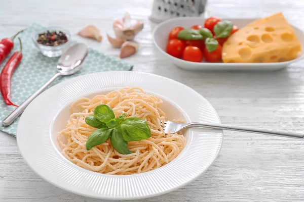 Talerz spaghetti i bazylia na stole. Makaron przepisy kulinarne — Zdjęcie stockowe