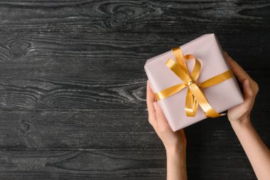 Hediye kutusu ahşap arka plan, üstten görünüm üzerinde tutan kadın
