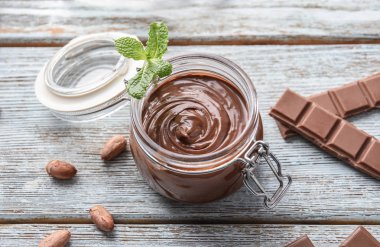 Ahşap masa üzerinde lezzetli eritilmiş çikolata ile Cam Kavanoz