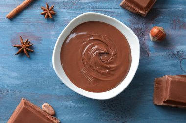 Ahşap arka plan üzerinde lezzetli eritilmiş çikolata ile kase