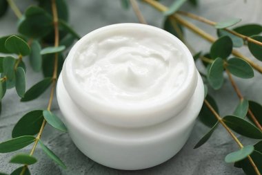 Gri arka planda, closeup bitkisel özü ile krem kavanoz