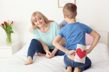 Küçük çocuk annesi yatak odasında arkasından için el yapımı kart gizleme