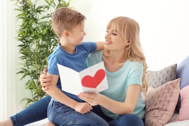 Sevimli küçük çocuk ve el yapımı kart evde annesiyle portre