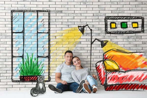 Giovane coppia sognando di trasferirsi in una nuova casa su sfondo muro di mattoni — Foto Stock