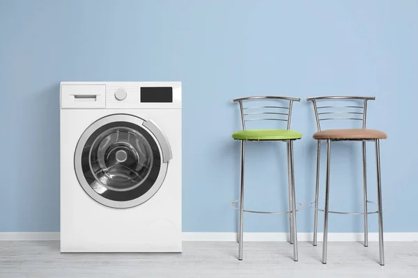 Сучасні пральні машини і барні стільці біля кольорової стіни в приміщенні. День прання — стокове фото