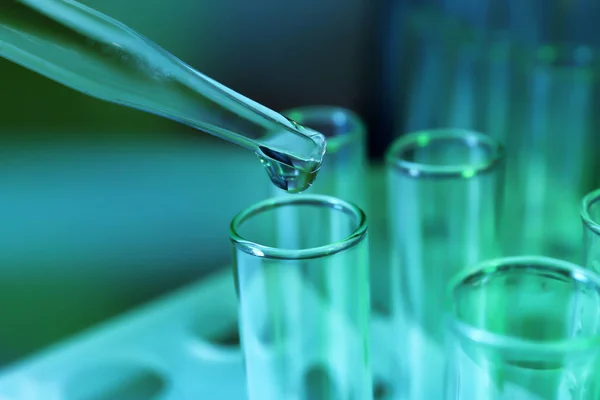 Pipette dripping sample into test tube on color background, closeup — Stock Photo, Image