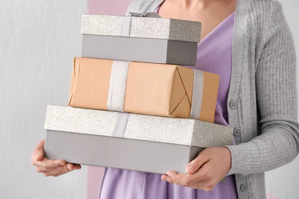 Woman holding gift boxes on color background, closeup — Stock Photo, Image
